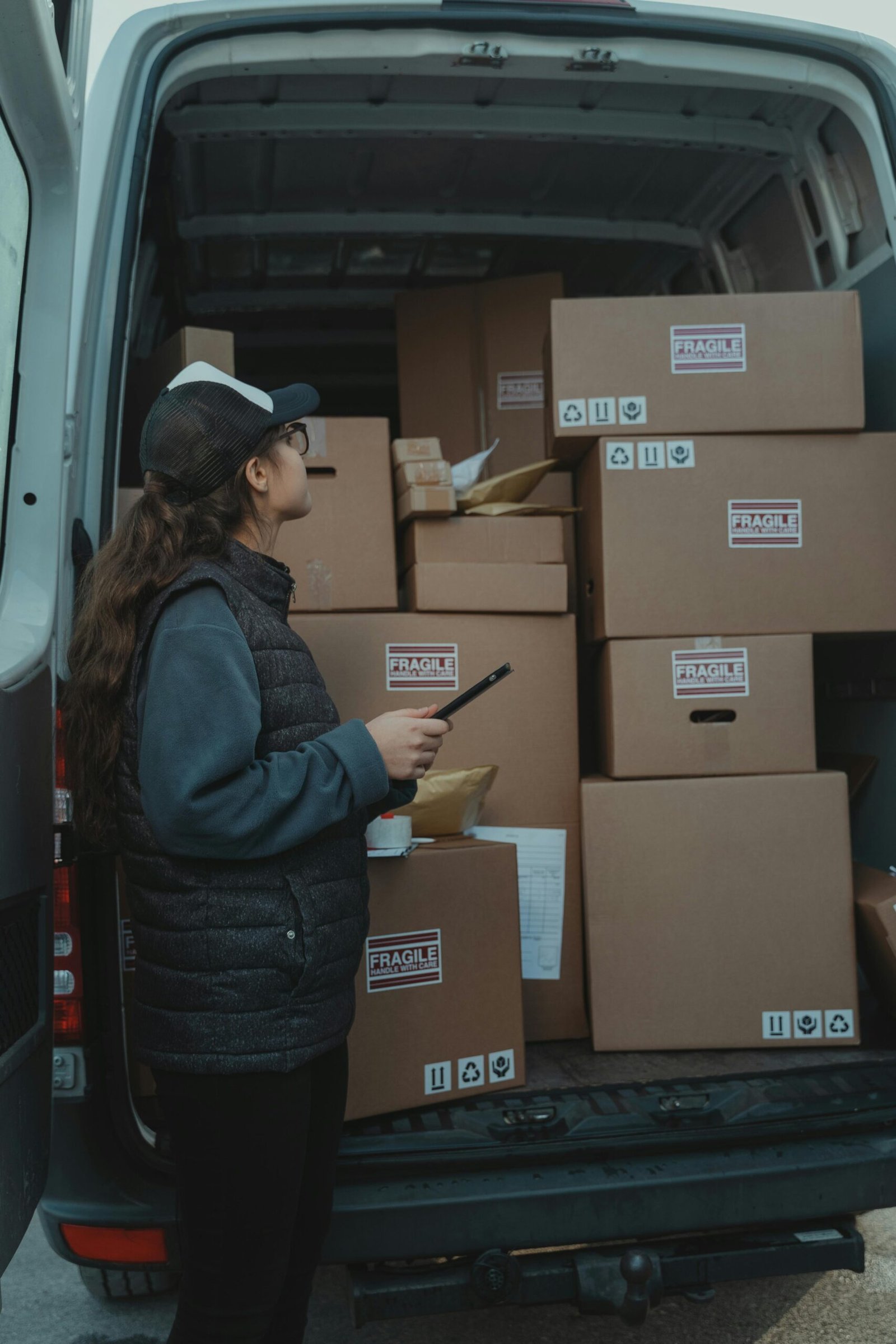 A female delivery worker organizing packages marked fragile in the back of a delivery van.
